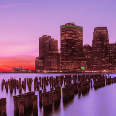 Autocollant - View from the water of the bay on the night city center of New York at sunset. Skyscrapers glowing in the dark against the sunset sky.