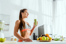 Low Angle View Of And Happy Woman Holding Glass With Green Smoothie