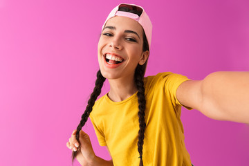 Sticker - Image of lovely teenage woman wearing casual t-shirt smiling and taking selfie photo