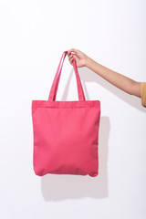 Wall Mural - Girl is holding pink bag canvas fabric for mockup blank template on white background. global warming concept.