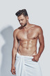© G-Stock Faces - Handsome young shirtless man covered with towel posing while standing against grey background