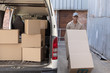 © WavebreakMediaMicro - Delivery man carrying cardboard boxes on trolley near van outside the warehouse
