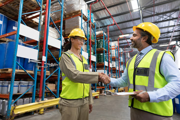 Wall Mural - Male and female staff shaking hands with each other in warehouse