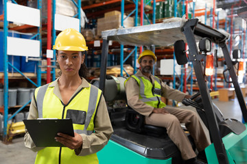 Female staff writing on clipboard in warehouse