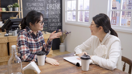 Young attractive woman applicant during job interview in coffee shop talking with hand gesture asking for manager opinion. two ladies interviewer and candidate having good time hire human resource