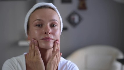 Wall Mural - Beautiful woman with perfect smooth healthy skin applies moisturizer on her face