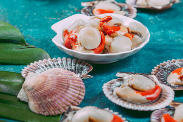 Raw fresh seafood shellfish scallops on blue background