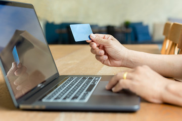 businessman hand holding credit card and using laptop on wooden table.