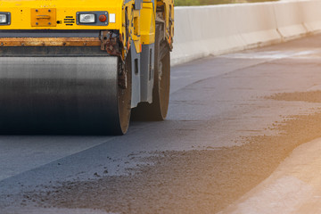 Asphalt road surface is smoothed with steel wheels, road construction machinery, asphalt paver