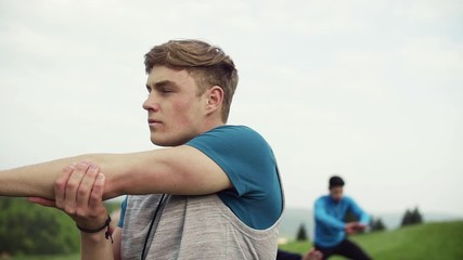 Sticker - A portrait of young man with large group of people doing exercise in nature.