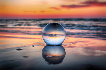 Wall Mural - Beautiful sunset on the beach in Slowinski National Park near Leba, Poland. View of a starfish through a glass, crystal ball (lensball) for refraction photography. Wild, untouched nature.