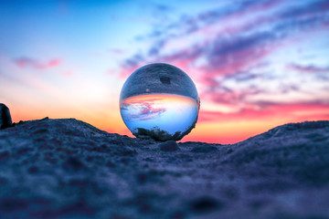Wall Mural - Beautiful sunset on the beach in Slowinski National Park near Leba, Poland. View of a starfish through a glass, crystal ball (lensball) for refraction photography. Wild, untouched nature.