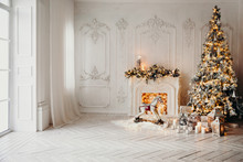 Classical Luxury Interior Of A White Room With Christmas Tree With Garland, Decorated Fireplace, Rocking Horse, Gifts For New Year