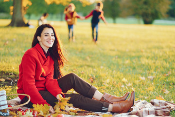 Wall Mural - Cute family in a autumn park. Happy mother with little kids. Family playing on yellow leaves. Golden autumn.