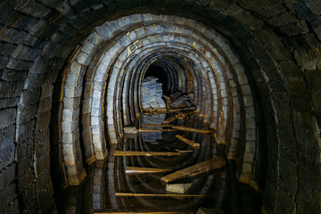 Canvas Print - Dark creepy dirty flooded abandoned mine tunnel with remnants of rusty railway