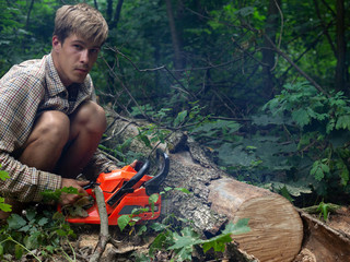 Canvas Print - young guy forester saws chainsaw trees in the forest