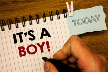 Wall Mural - Text sign showing It S A Boy Motivational Call. Conceptual photo Male baby is coming Gender reveal CelebrationMan creating for today on notebook Hand hold holding pen Wooden background