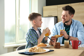 Wall Mural - Dad and son having breakfast together in kitchen