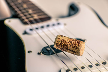 Electronic black and white guitar cluse up with wine cork on guitar strings.