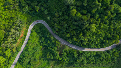 Wall Mural - aerial above view green mountain forest in the rain season and curved road on the hill connecting countryside