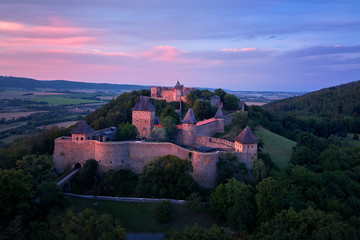 Wall Mural - Helfstyn castle (German: Helfenstein, Helfstein), aerial view of a medieval gothic castle on a knoll over countryside. Castle walls in vibrant colors of setting sun. Czech landscape, Moravia region.