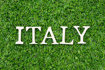 Wood alphabet letter in word italy on green grass background