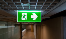 Green Fire Escape Sign Hang On The Ceiling In The Office.