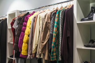 Colorful selection of clothes for men and women hanging on hangers in a mall for a store sale concept.