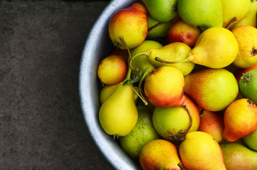 Wall Mural - Fresh ripe organic pears in a metallic bowl on a dark stone background.Autumn harvest,fruits or gardening concept.Copy space.Selective focus.