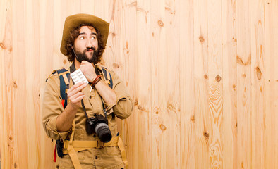 young crazy explorer with straw hat and backpack on wood backgro