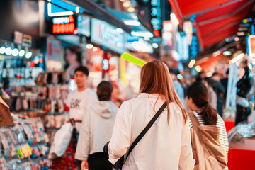 local travel activity concept from asian woman shopping and eat street food at night of south korea market