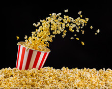 Flying Popcorn From Striped Bucket Isolated On Black Background