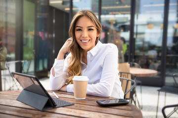 Portrait of a beautiful mixed ethnicity latin female student entrepreneur, working from laptop at coffee shop