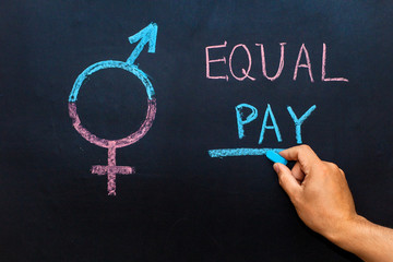 The pay gap and the symbol of gender equality are depicted on the chalkboard. Man's hand with chalk. The concept of gender equality.