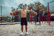 © zamuruev - Athletic man working out with a kettlebell at street gym yard. Strength and motivation. Outdoor workout. Exercise for shoulders.