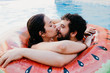 © EGHStock - Young couple on inflatable watermelon in swimming pool at hotel. Woman kisses her boyfriend nose. Summer holiday, lifestyle concept. Love moment.