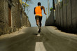 © TheVisualsYouNeed - Back view of athletic black African American professional sport man running training hard outdoors on asphalt road during jogging workout in healthy lifestyle