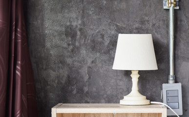 White table lamp on desk isolated on black wall background.