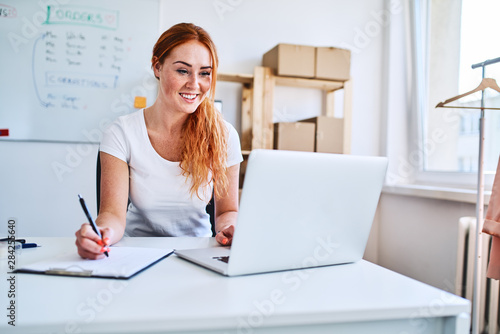 Fotomural Female online business owner using laptop and documents in small office