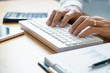 © Pichsakul - Close-up of male hands typing on keyboard Working On Compute Sitting Table And Office Tools At Workplace, writing emails, communicating online concept.