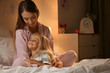 © Pixel-Shot - Happy woman with her little daughter on bed in evening