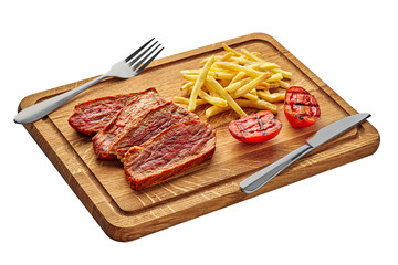 Delicious medium rare steak with French fries and grilled cherry tomatoes on a cutting board with table knife and fork. Classic meat meal isolated on white background.