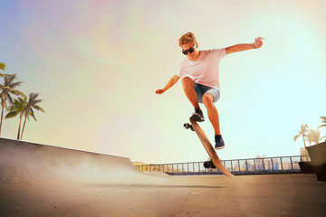 Skateboarder is performing tricks in skatepark on sunset.