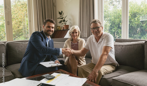 Fotomural Active senior man shaking hands with real estate agent in living room