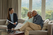© wavebreak3 - Active senior couple discussing with real estate agent over documents in living room