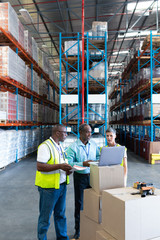 Warehouse staffs discussing over laptop in warehouse