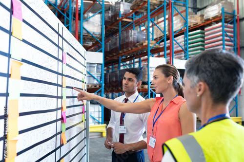 Fotomural Warehouse staffs discussing over whiteboard in warehouse