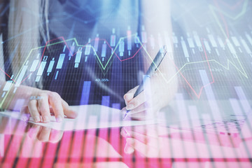 A woman hands writing information about stock market in notepad. Forex chart holograms in front. Concept of research.