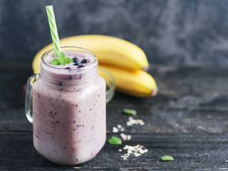 Wall Mural - A jar of dark smoothie with blueberries and banana on a wooden table