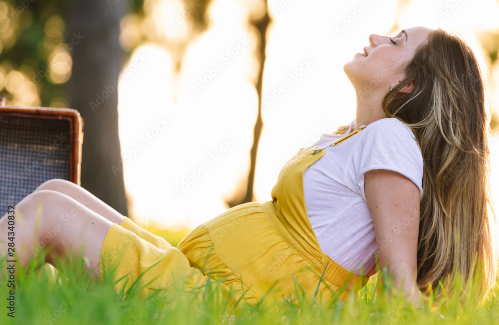 Young pregnant girl at a picnic at sunset. Feeling good